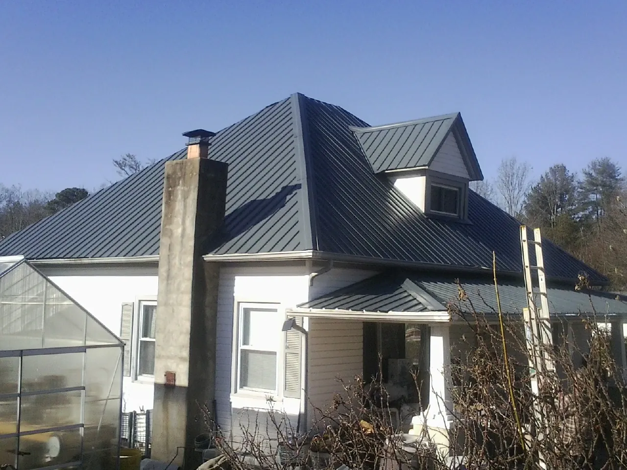 Dark blue standing seam metal roof on a white farmhouse with dormer — Slate & Tile Roof Repair by Roofing Brothers in Gallipolis