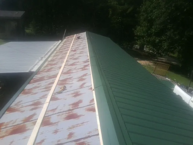 Old rusted panels beside newly installed green metal roofing — Wind Damage Roof Repair by Roofing Brothers in Gallipolis