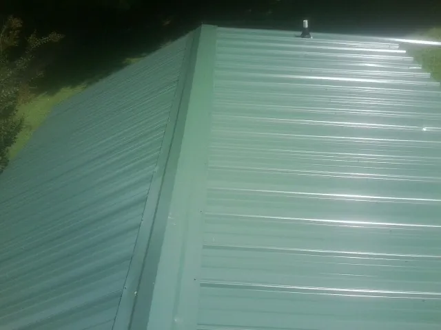 New green metal panels meeting at the ridge of a roof — Flat Roof Repair work by our crew in Gallipolis