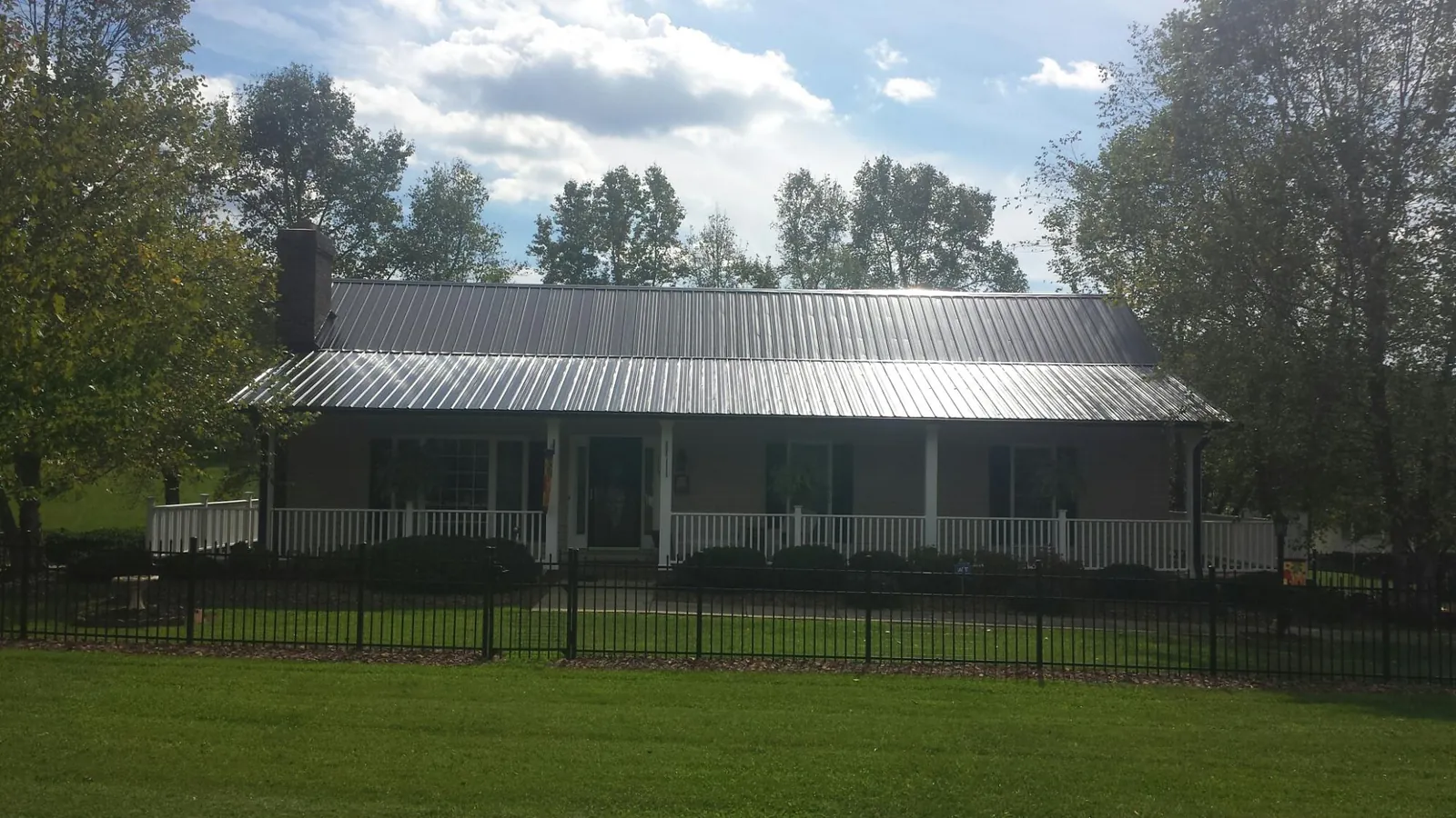 Gray metal roof on a brick ranch with a full width front porch — Gutter Guard Installation work by our crew in Gallipolis