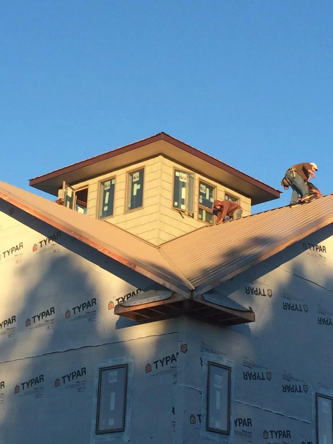 Roofers working around a rooftop cupola on a new metal roof at sunset — Roof Waterproofing in Gallipolis by Roofing Brothers